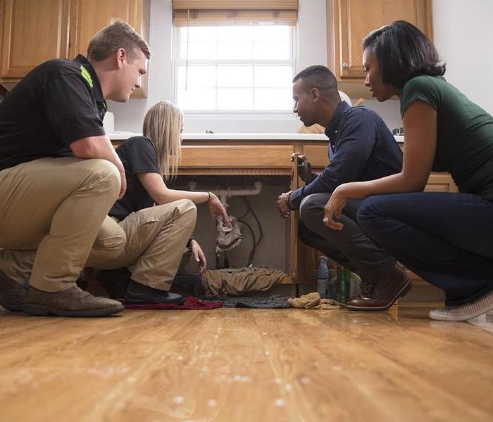 SERVPRO technicians and clients in flooded kitchen